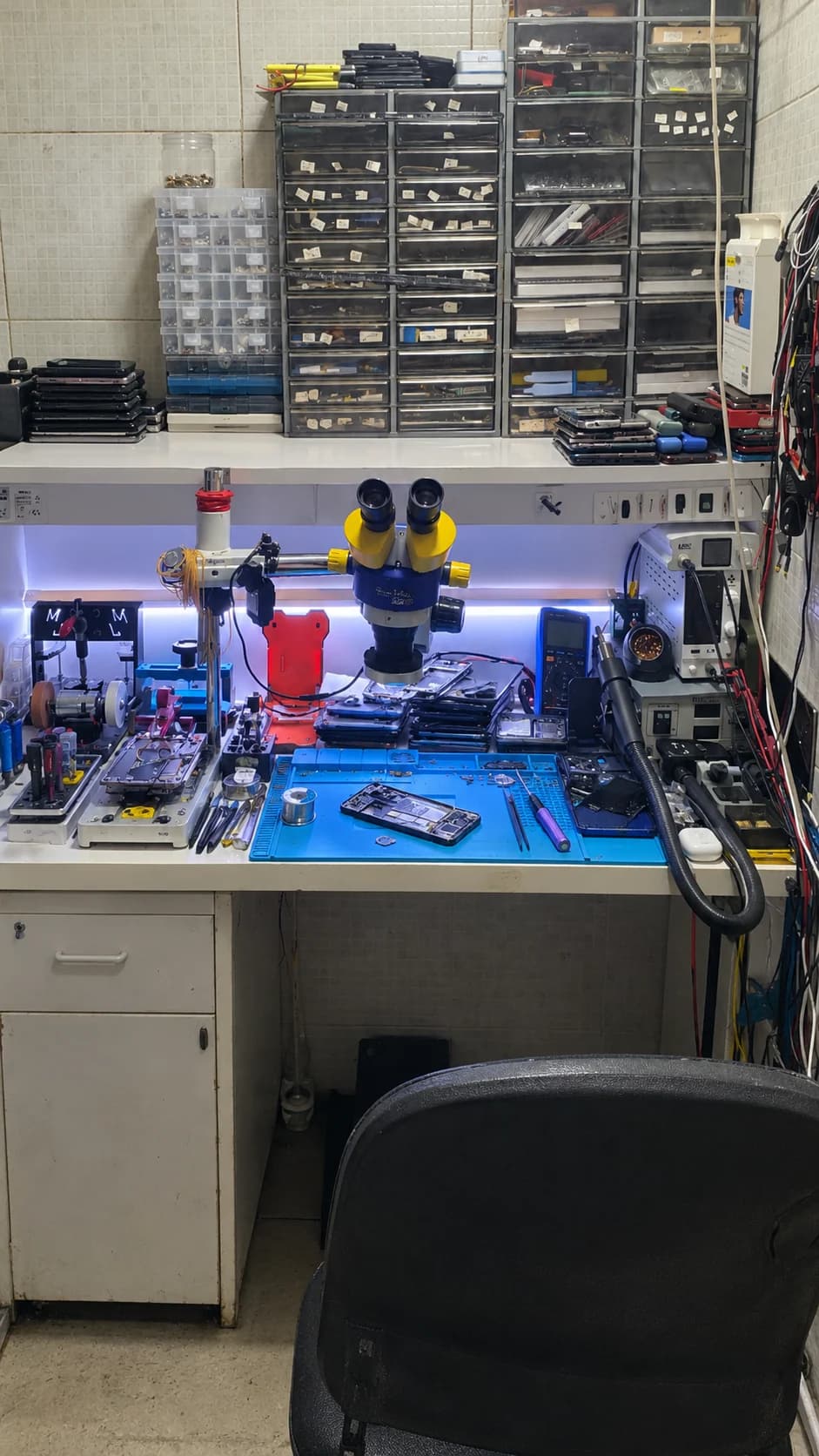 Technochips repair bench with a microscope, phone repair tools and devices.